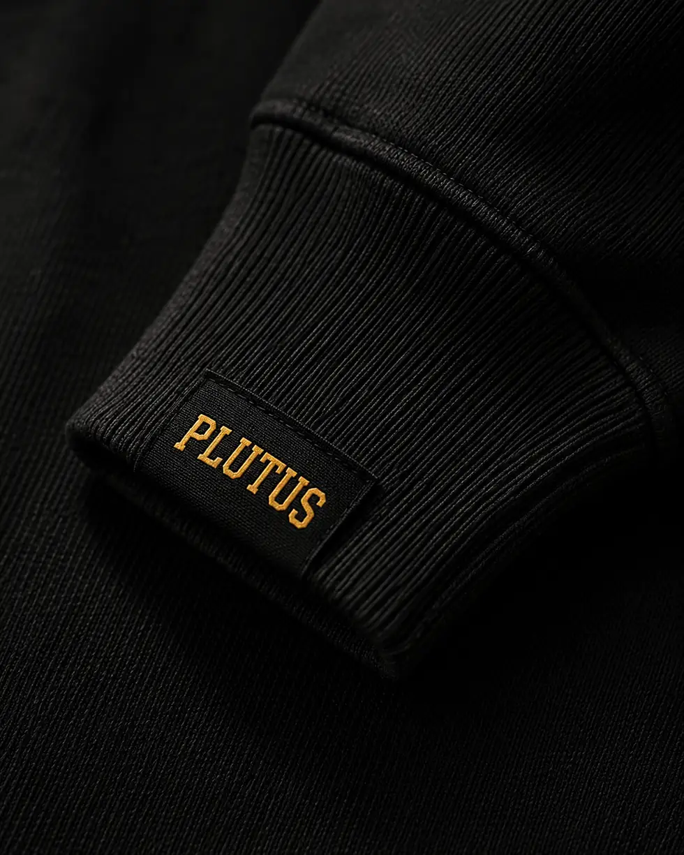 A woven PLUTUS label stitched to a ribbed cuff.