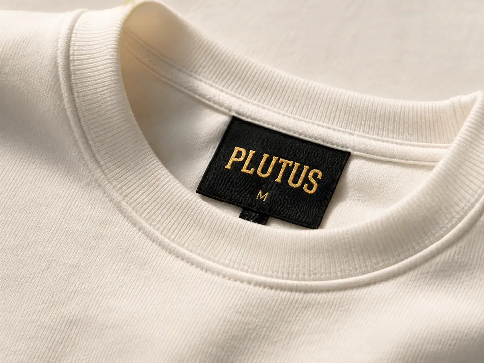 The neck label inside a bone crewneck, reading PLUTUS and a size.