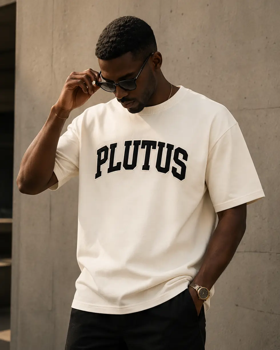 A man wearing the bone PLUTUS tee with the arched print in black.